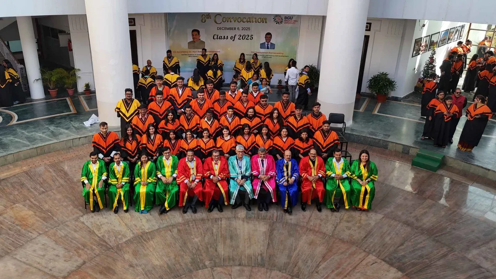 The graduating class in convocation robes posed on the steps beneath the Class of 2025 banner