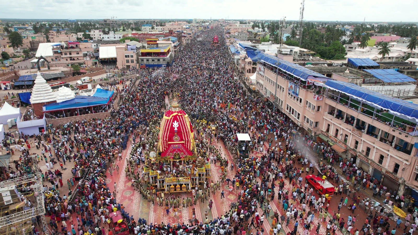 Aerial view of the Rath Yatra procession at Puri — the chariot on Grand Road with crowds filling the street to the horizon