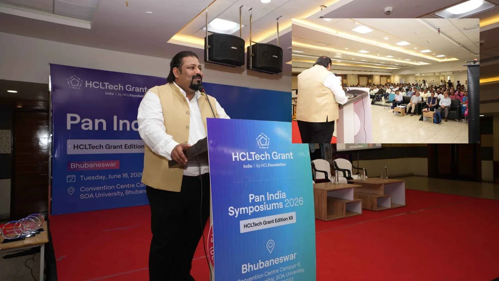 A speaker at the lectern at the HCLTech Grant Pan India Symposium, with a wide shot of the seated audience inset