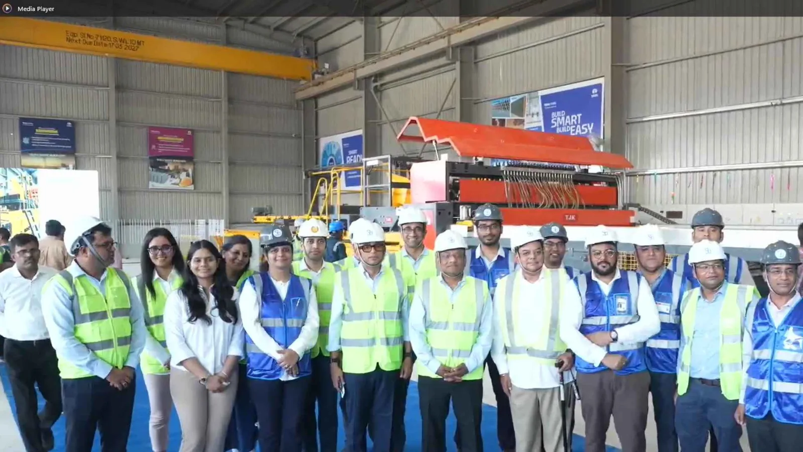Site visit group in hi-vis vests and hard hats photographed inside the industrial shed