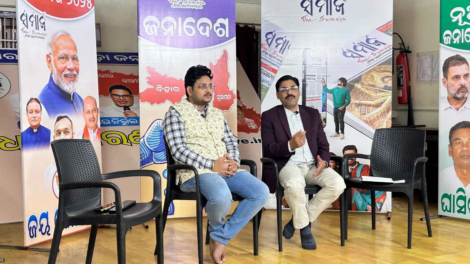 Three guests seated on the podcast set in front of a backdrop of Odia newspaper mastheads